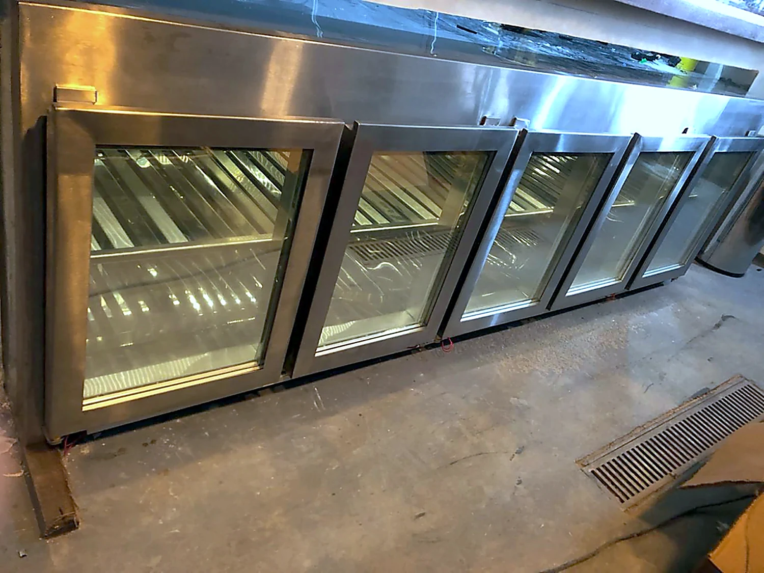Linha de refrigeradores em inox com portas de vidro alinhados na área de produção antes da entrega
